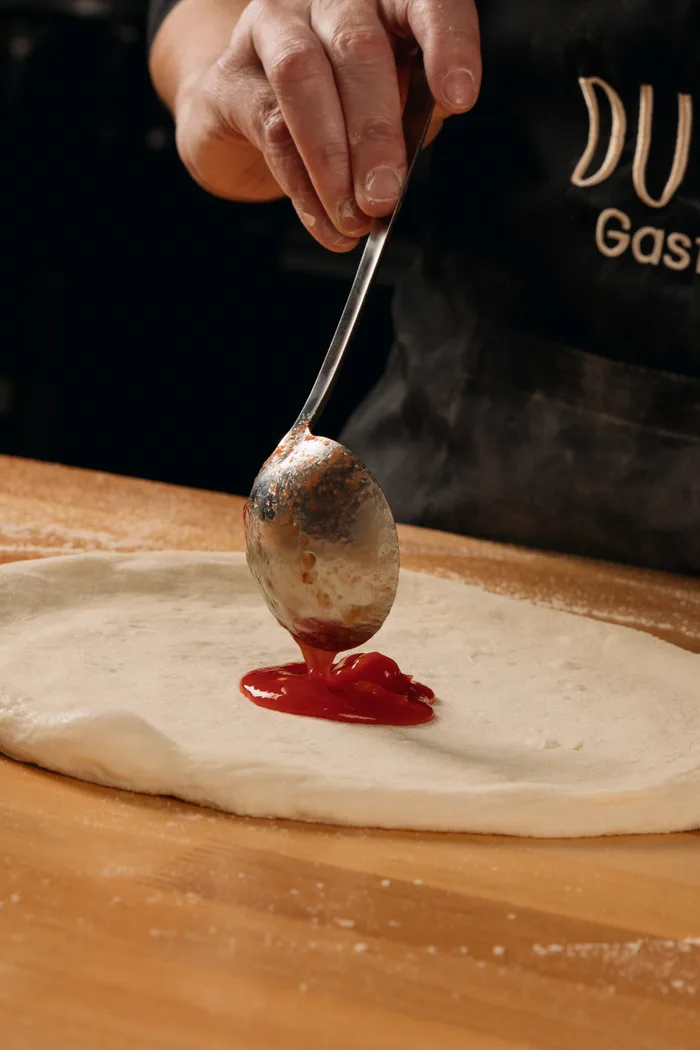 Molho sendo colocado na massa da pizza