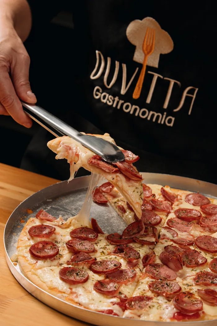 Pizza de calabresa sendo servida